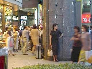 大理石の柱にもたれて人を待つ女性