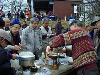 頂上での食事の準備。漆戸さんの手際良さにみんなが注目。